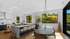 A modern kitchen with a central island, bar stools, and a dining table with chairs. - Resolute Ridge Meadow House (Bozeman)