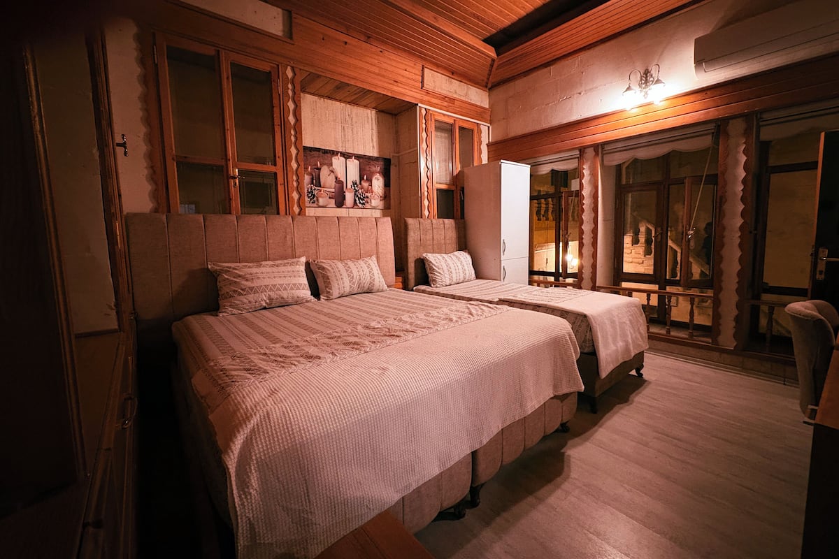 Un dormitorio acogedor con dos camas, cabeceros de madera y un ventanal grande.