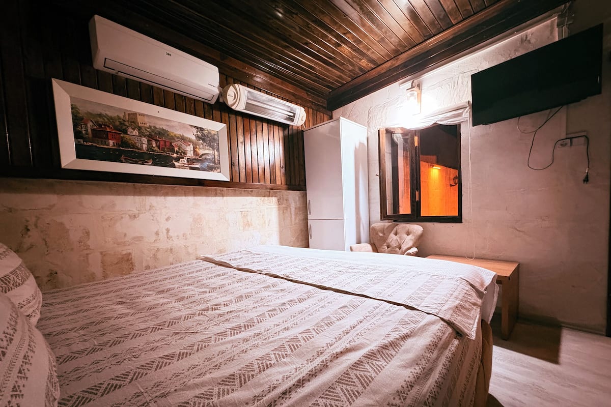 Un dormitorio con una cama, una silla, un espejo y un televisor en la pared.