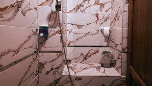 A bathroom with marble tiles, a wooden ceiling, and a shower with a handheld showerhead. - toprak konak (Şanlıurfa)