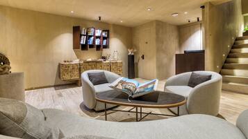 A modern living room with a sofa, armchairs, a coffee table, and a bookshelf.