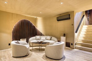 A modern interior with a curved wall, a staircase, and a sofa set. - Casa Tasman (Mexico City)