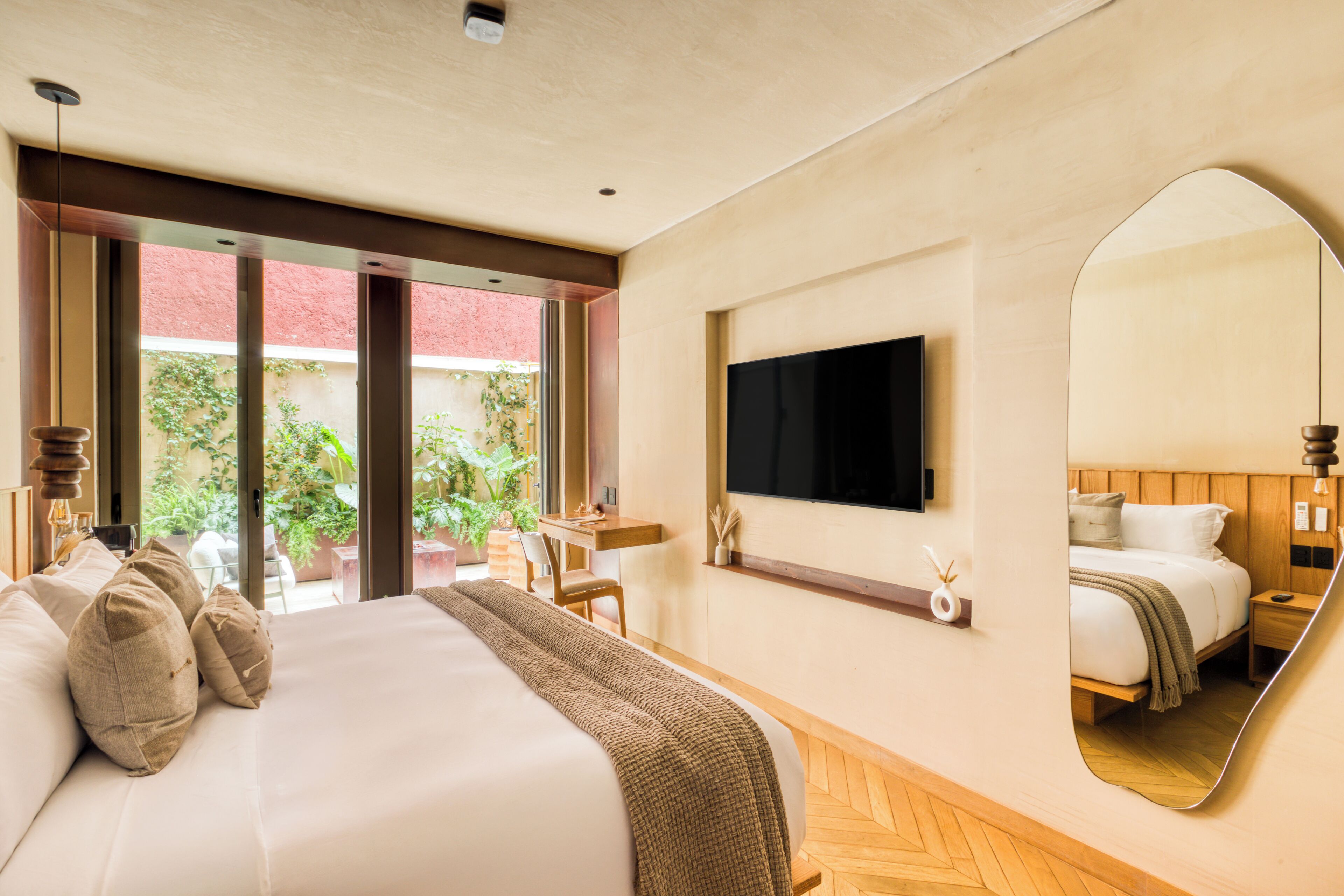 Ein Hotelzimmer mit einem großen Bett, einem Schreibtisch, einem Fernseher und einem Spiegel.