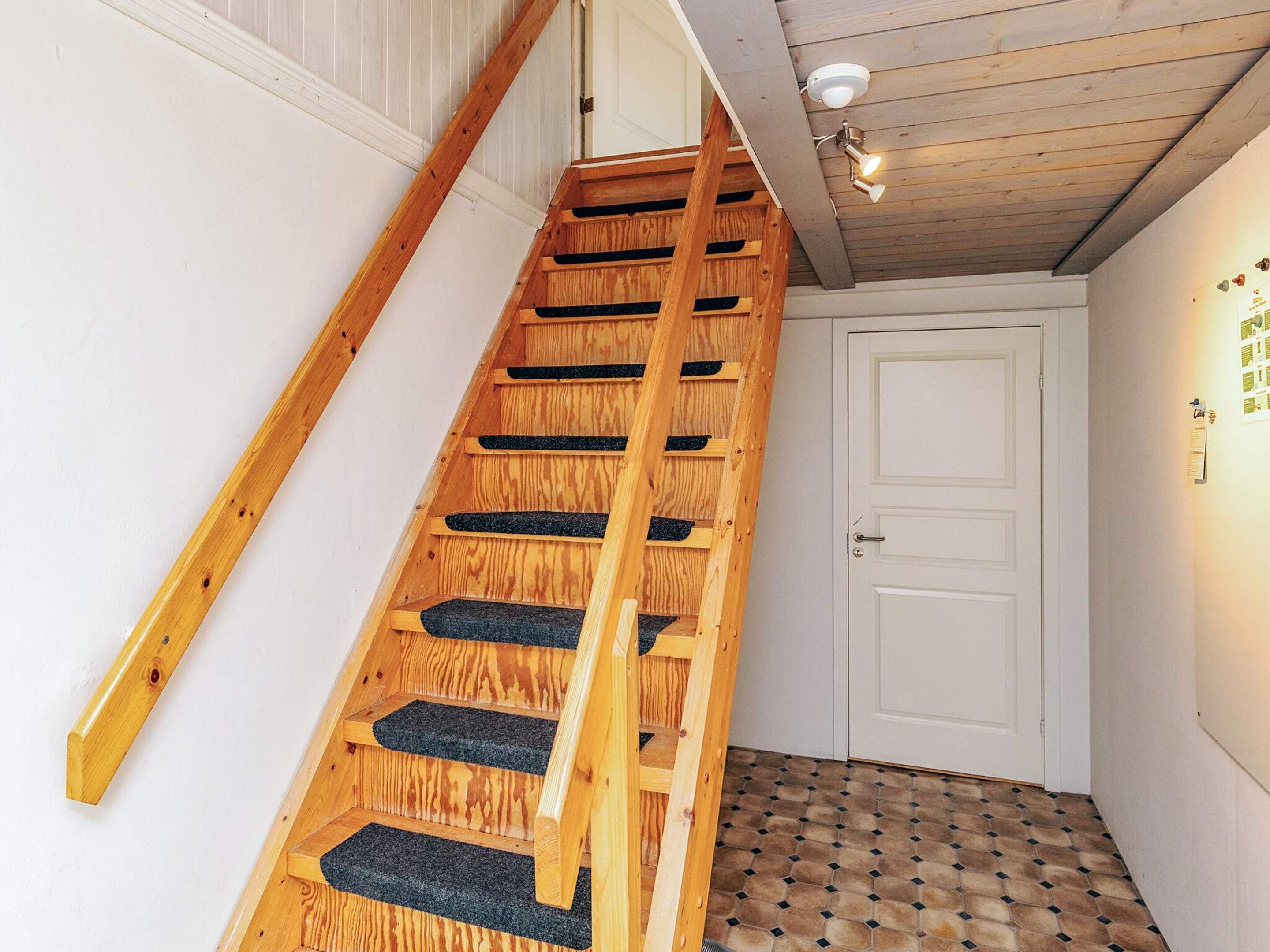 A wooden staircase with a handrail leading to a white door.