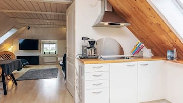 Una cocina moderna con techo de madera, armarios blancos y una cafetera.