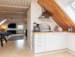 A modern kitchen with a wooden ceiling, white cabinets, and a coffee machine.