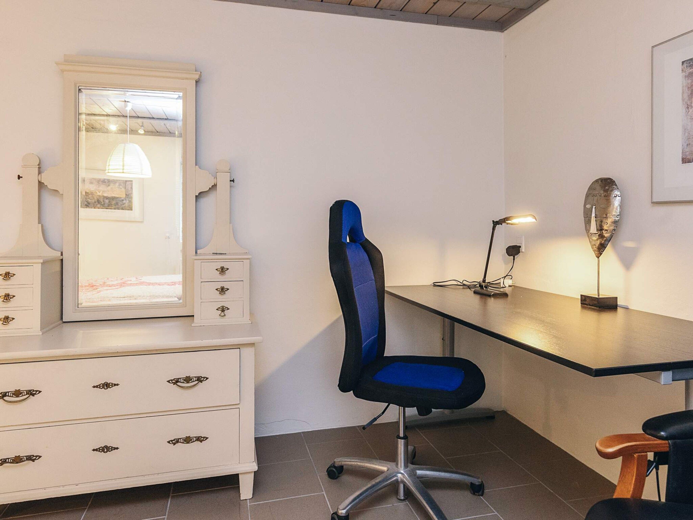 Une pièce comprenant un bureau, une chaise, une commode et un miroir.