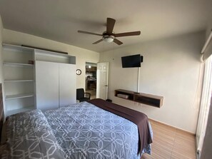 A bedroom with a bed, a ceiling fan, a TV mounted on the wall, and a wardrobe. - Nice first floor apartment, air conditioning, access to pool and 10 min from the beach. (Manzanillo)