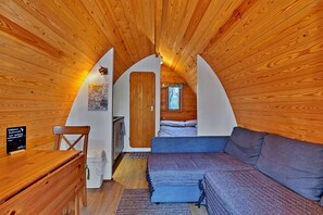 Een gezellig slaapkamer op zolder met houten wanden, een bed, een bank en een klein bureau.