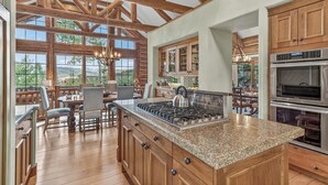 A spacious kitchen with granite countertops, wooden cabinets, and a large island. - Luxury Ski-in/out Retreat | Timber Haven (Avon)