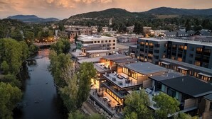 Un hôtel situé au bord de la rivière, doté d’une architecture moderne, offrant une vue sur le fleuve et s’inscrivant dans un paysage montagneux.