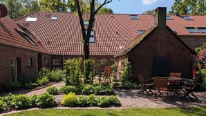 Ein Ziegelhaus mit Ziegeldach, ein Garten mit verschiedenen Pflanzen und Gartenmöbeln.