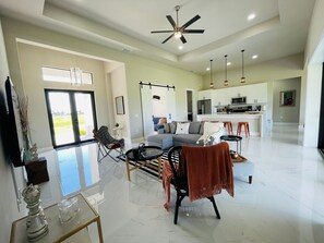 A spacious living area with a modern kitchen, a dining area, and a large sliding glass door leading to a balcony. - Xlhouse Safe Comfortable Perfect for Big Families (Cape Coral)