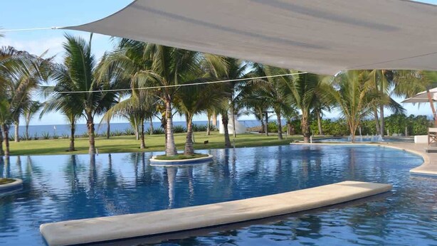 A swimming pool with palm trees and a view of the ocean. - Private jacuzzi and balcony in 2-Br villa (Monterrico)