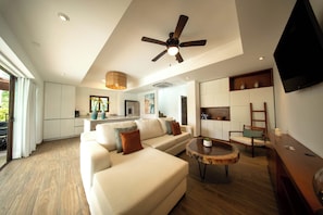 A modern living room with a ceiling fan, a sofa, a coffee table, and a TV mounted on the wall.