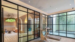 A modern interior with a large sliding glass door, a treadmill, and a dining area with a round table and chairs. - Magnotel Guilin Elephant Trunk Hill (Guilin)