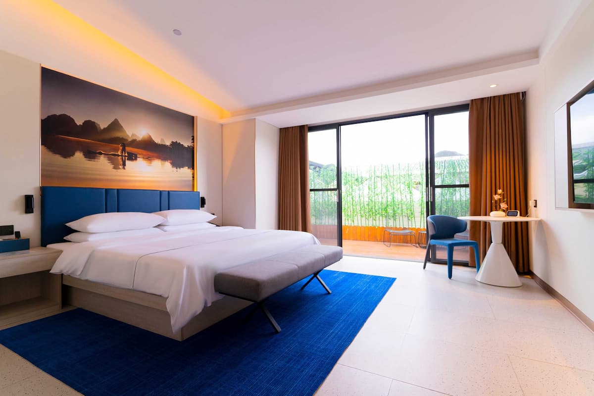 Une chambre d’hôtel moderne, dotée d’un grand lit, d’un bureau et offrant une vue sur l’extérieur.