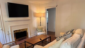 Un salon avec une cheminée, un canapé, une table basse et un téléviseur fixé au mur.