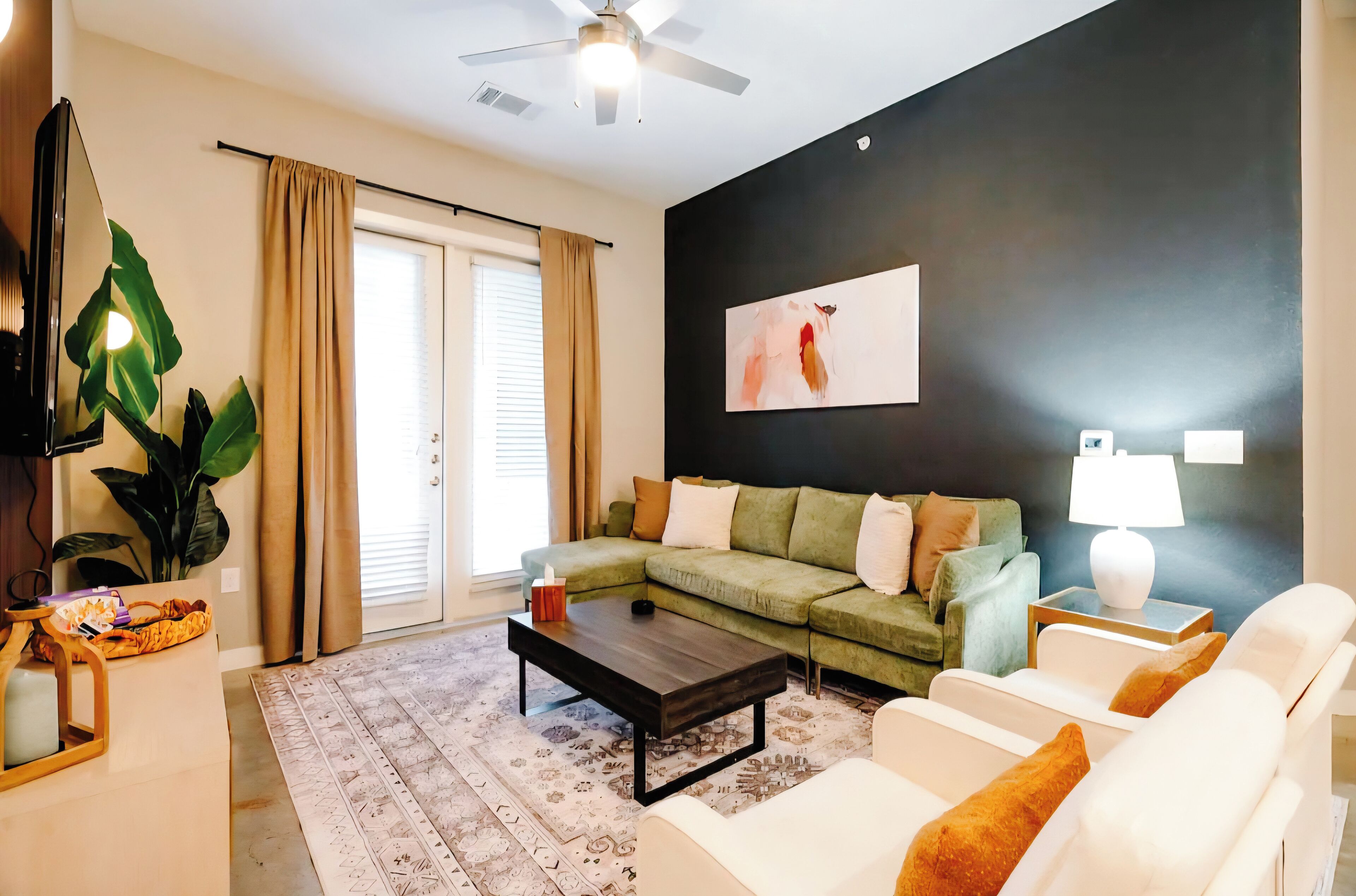 Un salon moderne avec un canapé d’angle, une table basse, un fauteuil blanc, une lampe sur pied et un grand tableau abstrait accroché au mur.