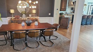 Un coin repas comprenant une table en bois, quatre chaises, un lustre et des objets décoratifs.