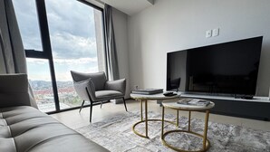 A modern living room with a sofa, a chair, a coffee table, and a TV.