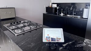 A modern kitchen with a gas stove, black cabinets, and a digital display listing amenities.