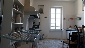 A kitchen with a window, shelves with kitchenware, and a chair.