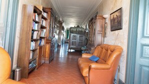 A hallway with a leather sofa, a bookshelf, and a cabinet.
