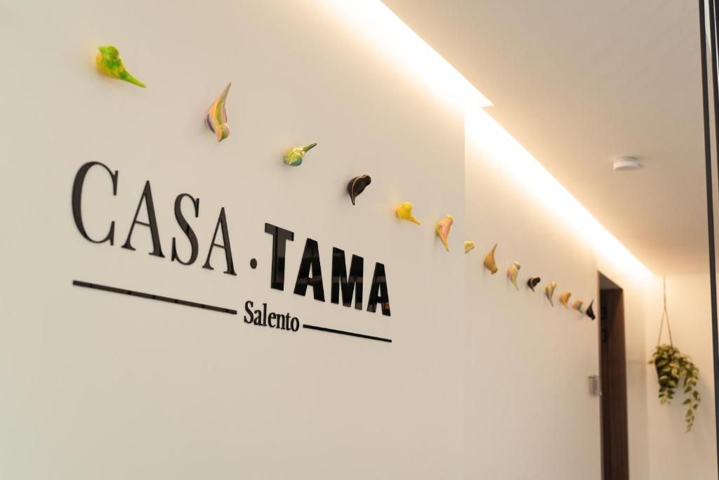 Una pared con el texto 'CASA TAMA Salento' y figuras decorativas de pájaros.