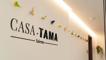 Una pared con el texto 'CASA TAMA Salento' y figuras decorativas de pájaros.