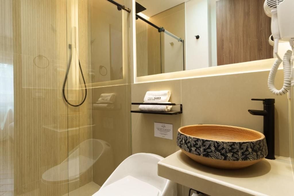 A modern bathroom with a glass shower enclosure, a white sink with a decorative bowl, and a towel rack with a towel.