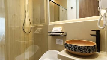 A modern bathroom with a glass shower enclosure, a white sink with a decorative bowl, and a towel rack with a towel.
