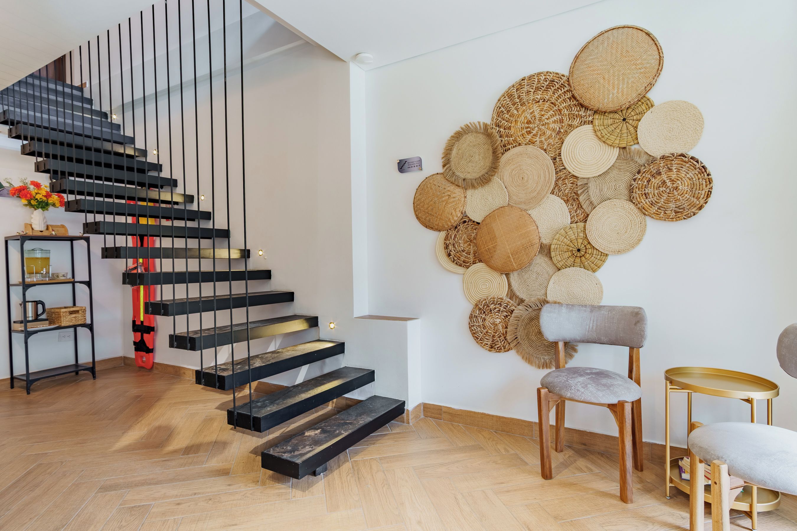 Ein modernes Interieur mit einer Wendeltreppe, einer Wand aus gewebten Körben und einer minimalistischen Sitzecke.