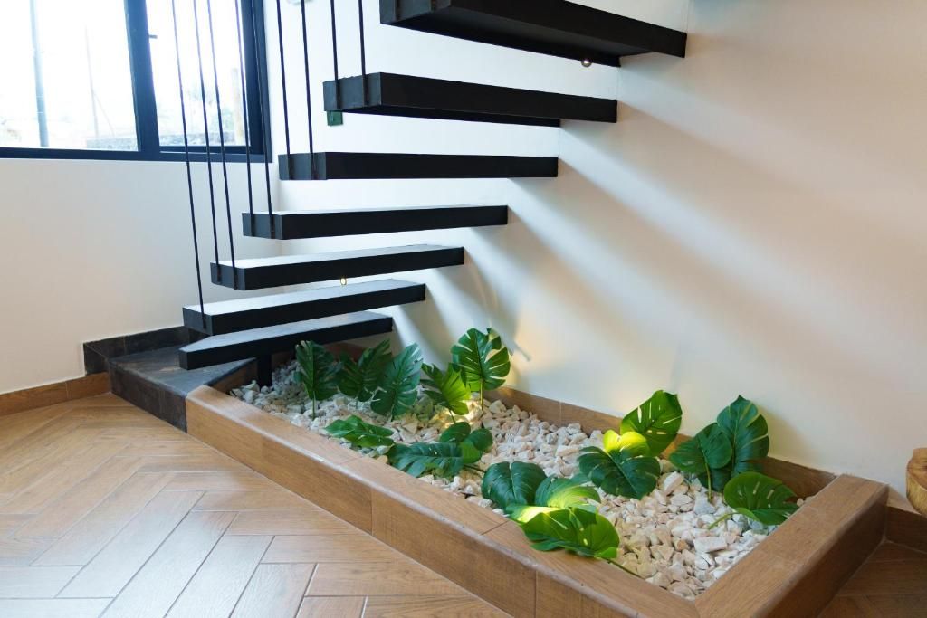 Una escalera moderna con escalones negros y un jarrón con plantas verdes.