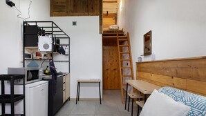 A compact room with a kitchenette, a bed, a ladder, and a wooden headboard. - Studio Apartment 'Il Nido Di Montagna' (Gressan)