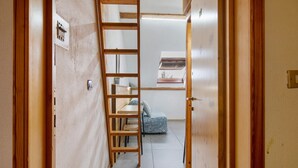 A narrow hallway with a wooden ladder, a small table with a cushion, and a door leading to another room. - Studio Apartment 'Il Nido Di Montagna' (Gressan)