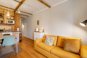 A compact living space with a kitchenette, a sofa with patterned cushions, and a dining area.