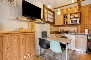 A kitchen with wooden cabinets, a microwave, a sink, and a dining area with chairs.