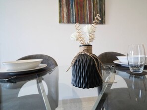Een eettafel met een decoratieve vaas, borden en bestek.