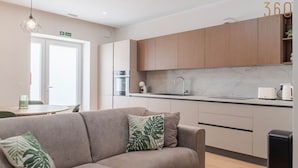 Eine moderne Küche mit Marmorarbeitsplatte, Holzschränken und einem eingebauten Backofen.
