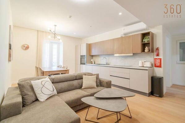 En moderne lejlighed med sofa, spisebord og et køkkenområde.
