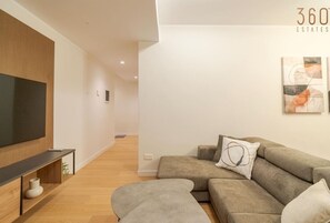 A modern living room with a flat-screen TV, a sofa, and a coffee table.