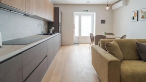 Una cocina moderna con armarios grises, encimera de mármol y un comedor con sofá y sillas marrones.