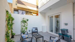 A small outdoor patio with two chairs, a table, and a vertical garden.