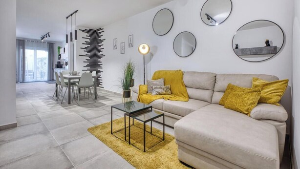 A modern living room with a sofa, coffee table, and dining area.