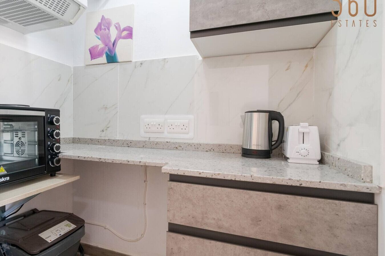 A kitchen with a marble countertop, a coffee maker, a toaster, and a microwave.