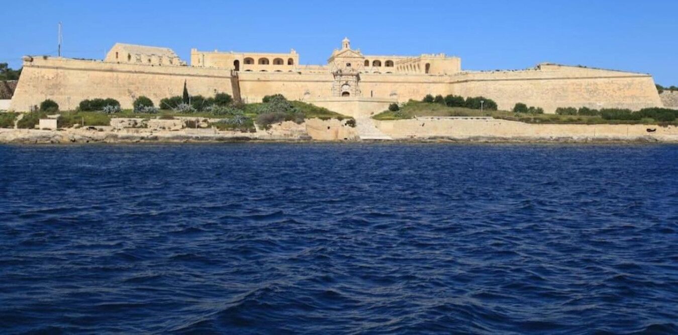 A large, fortified building with a central tower, situated by the sea.