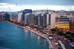 A coastal cityscape with a waterfront promenade, high-rise buildings, and a busy street with vehicles and pedestrians. - Sleek & Simple comfy Studio near Griza Promenade! (Gżira)
