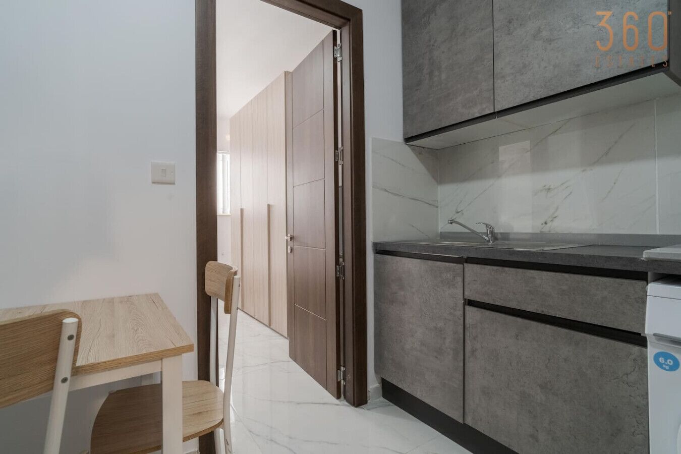 A modern kitchen with grey cabinets, a marble countertop, and a sink.