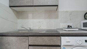 Eine kompakte Küche mit Einbauwaschmaschine, Mikrowelle und Spüle.